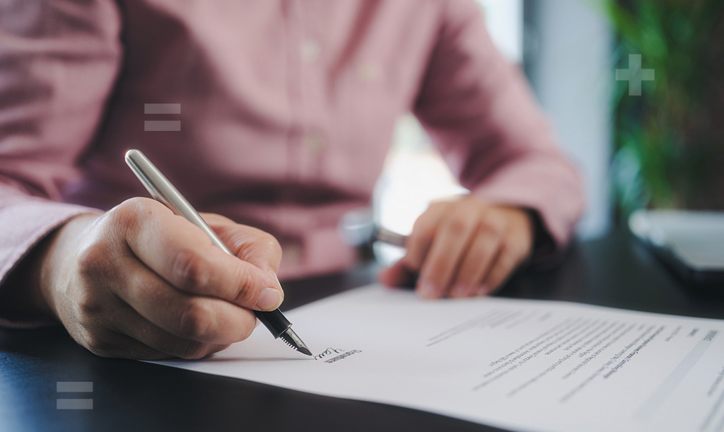 A hand holding a fountain pen and signing a document