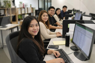 Five offshore accountants in the Philippines looking toward the camera from their workstations, delivering accounting services that support business growth.